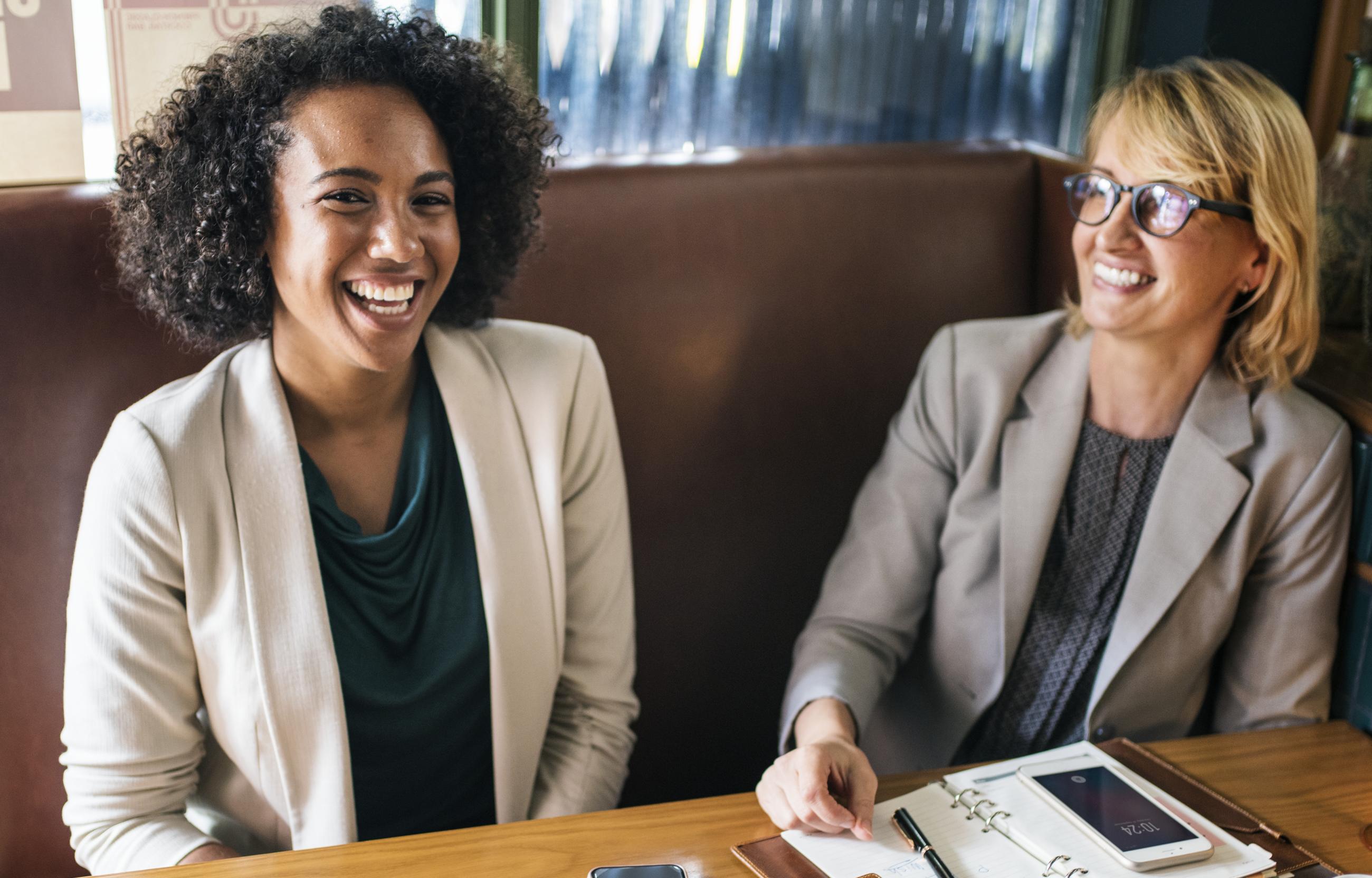 Two women at a desk smiling